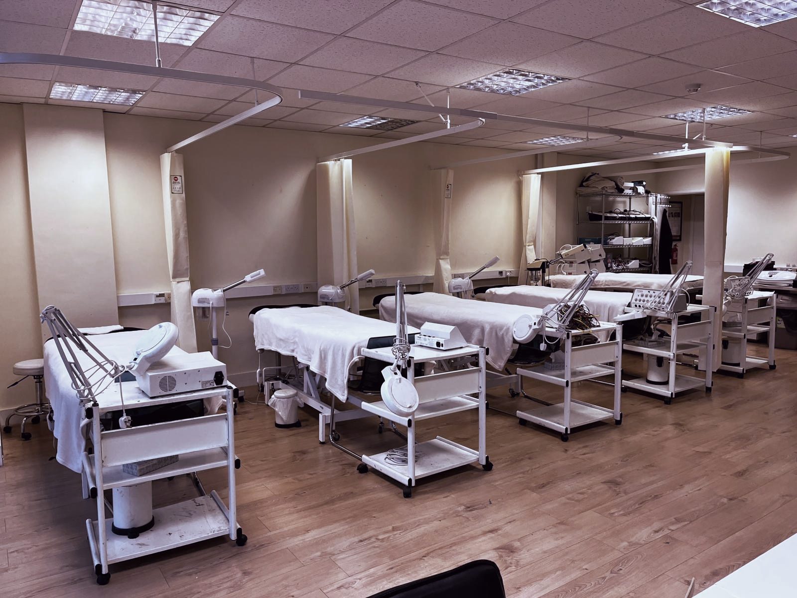 Treatment beds with lamps and equipment trolleys at the Feltham beauty salon