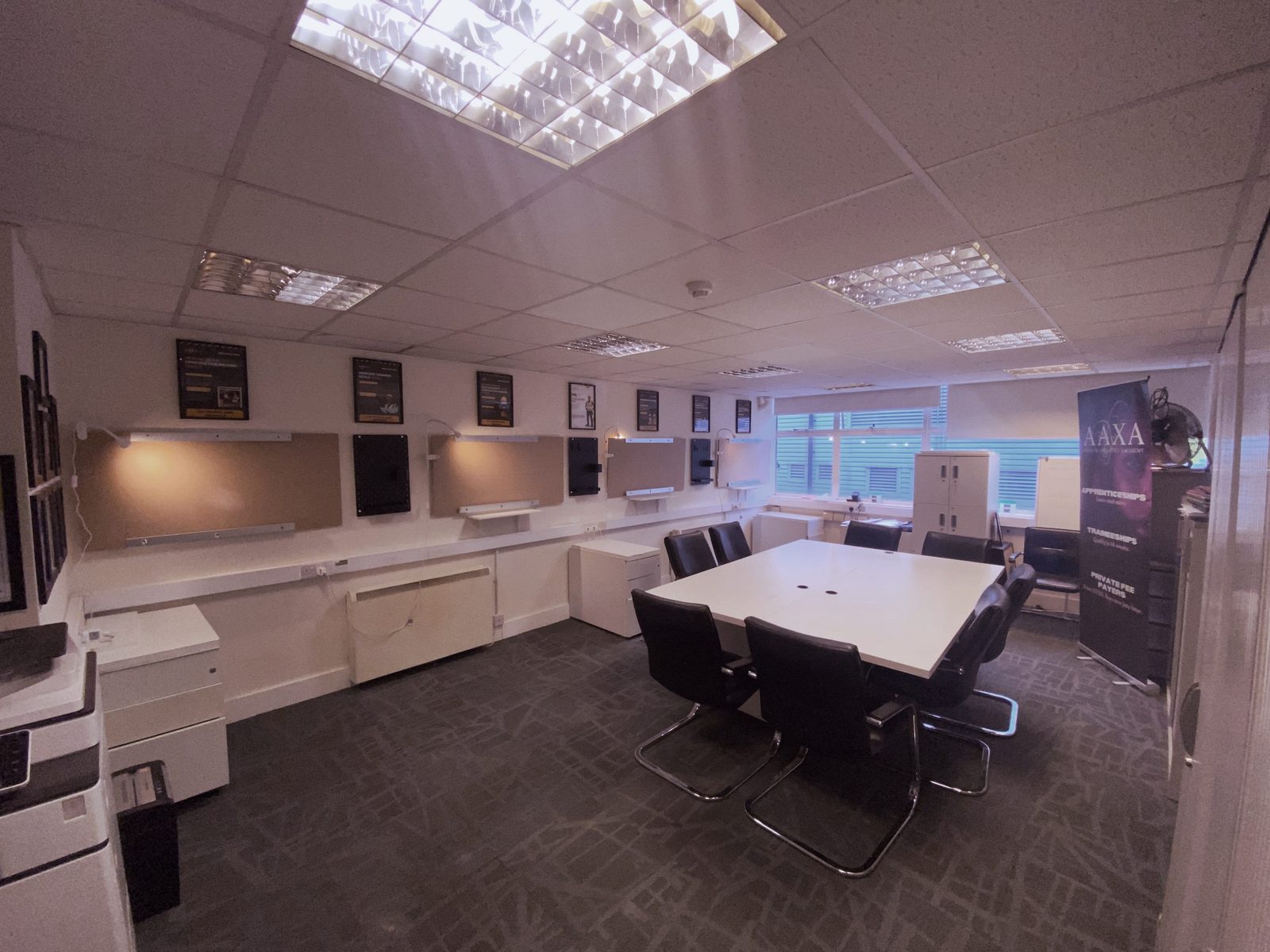 Wide view of the Feltham trade and construction room with practice boards, learning table and AAXA banner