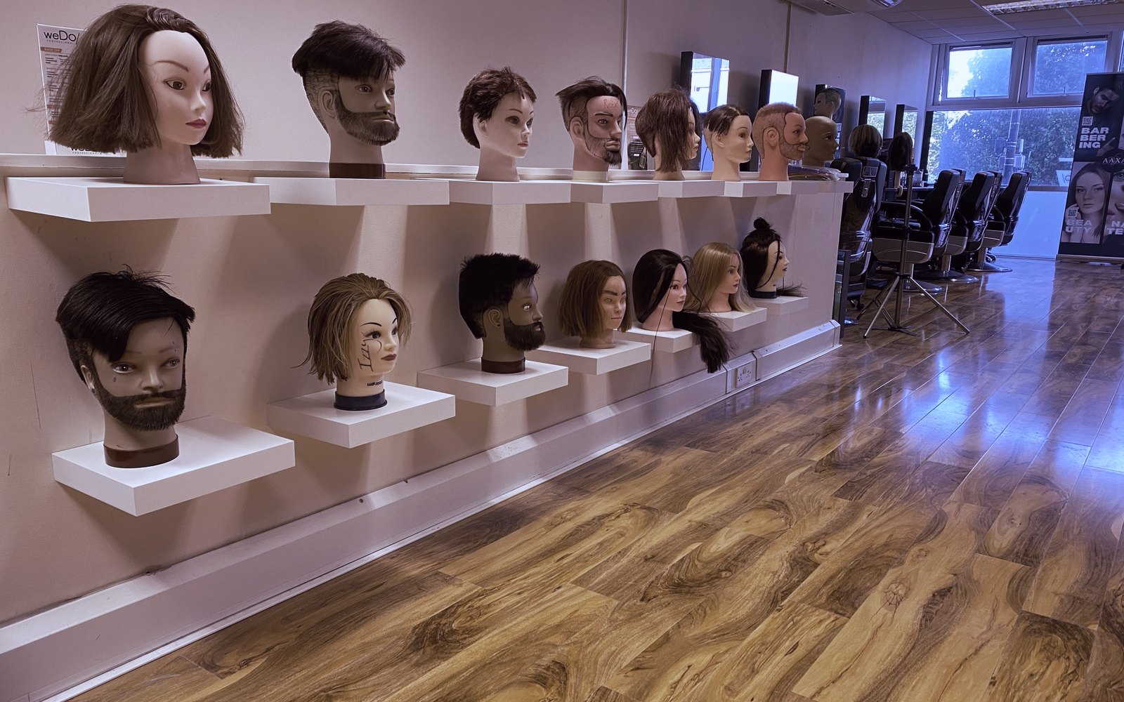 A wall of practice heads showing cuts and beard work at the Feltham hub
