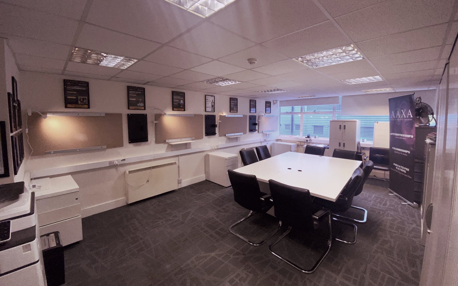 Wiring practice boards with task lamps and a group learning table at the Feltham trade and construction hub