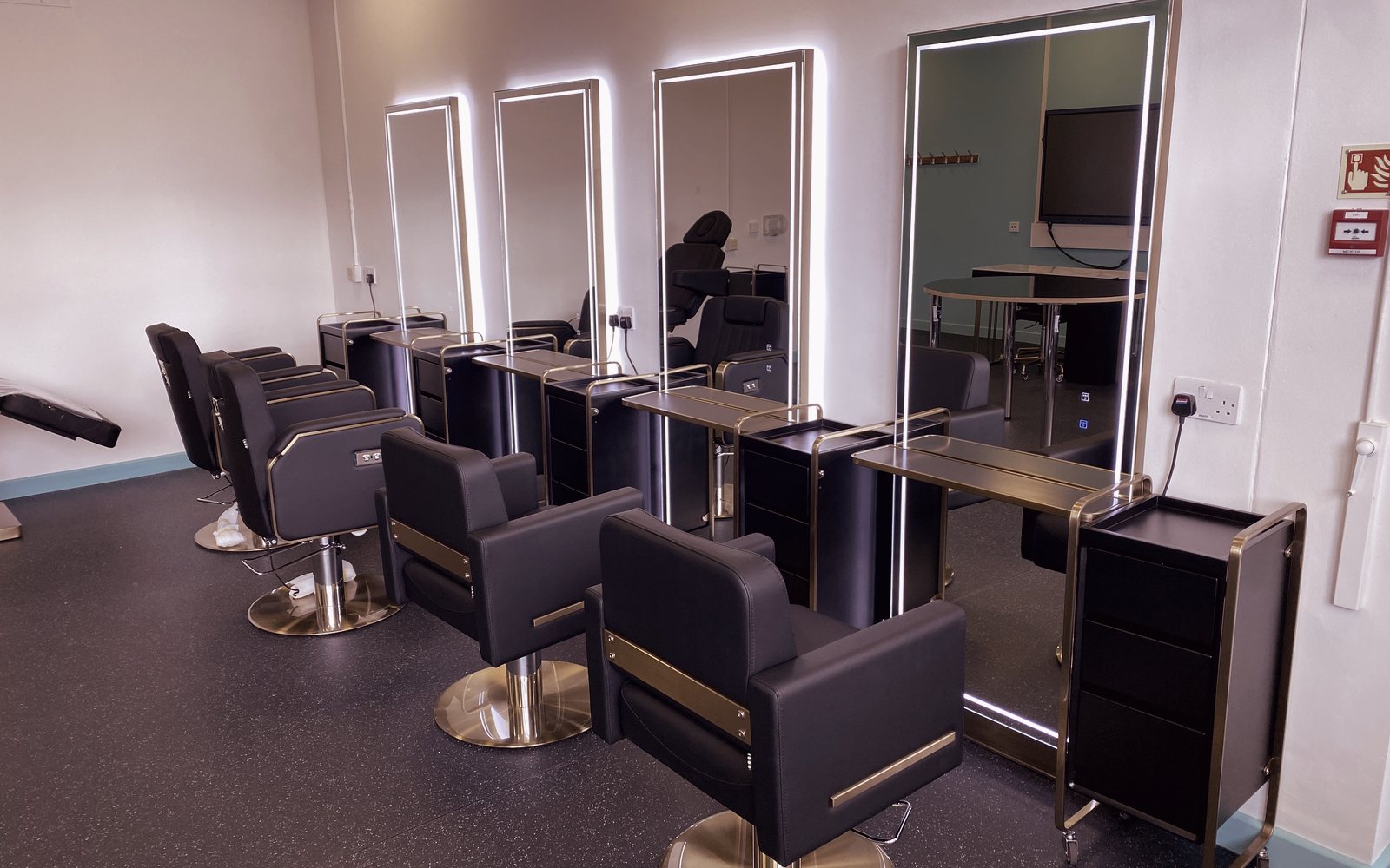 Gold-framed lit mirrors and styling chairs in the EAP-Extend partnership salon, Ealing