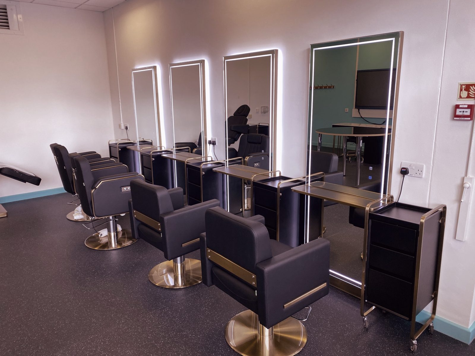 Lit mirrors and black and gold styling chairs at the Ealing partnership hub